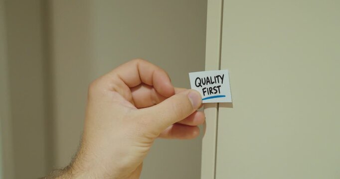 Person brings a Quality First card into view and sticks it on the wall as a quality reminder.