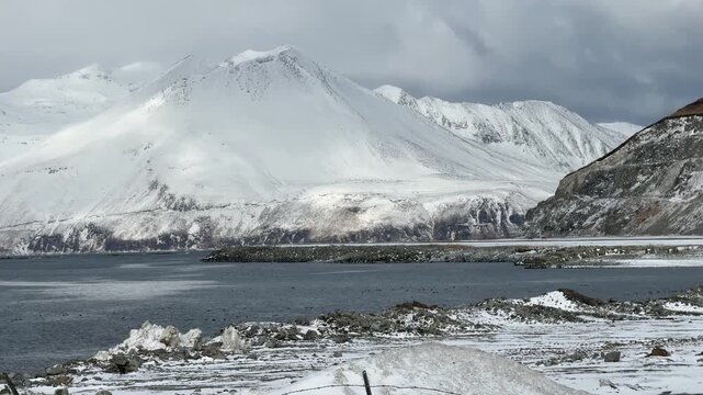 Slow tracking shot of Dutch Harbor airport runway with a small commuter aircraft flying out on a snowy day, Unalaska.