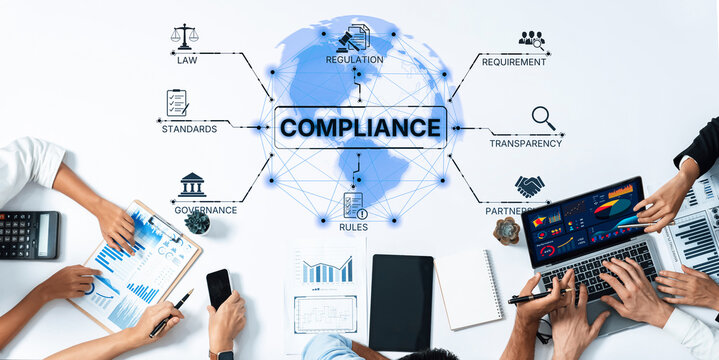 This image depicts a collaborative business meeting focused on compliance regulations, featuring charts, laptops, and diverse professionals in a modern office environment. Trope