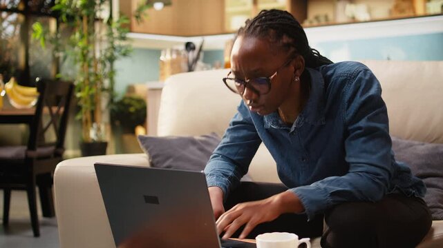 Woman freelancer works on online tasks with laptop at kitchen table, using wireless technology for a connected professional lifestyle. Teleworking supports productivity at home and freelance work.