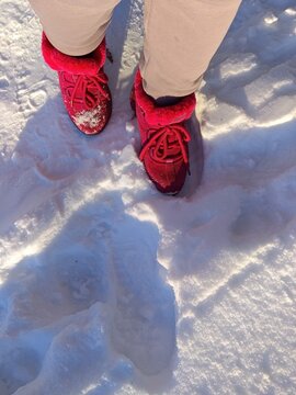 Bright pink boots in snow: cozy winter footwear on a sunny day