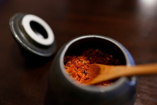 七味唐辛子が入った小さな陶器の器。木製さじ付き