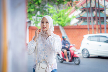 Obraz premium A young Asian Muslim woman wearing a bag and ethnic-style bracelets. Muslim model.