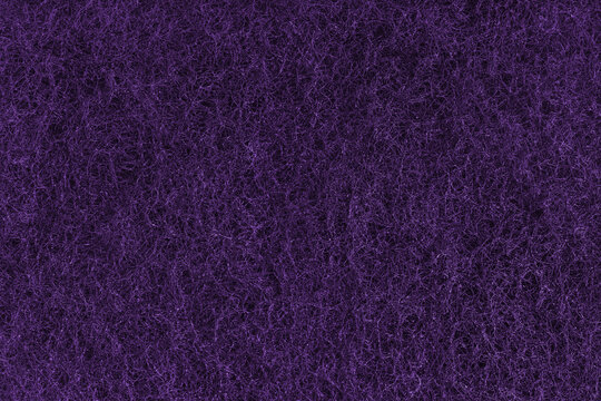 Abstract purple felt texture with dense fibers, fluffy structure of carpeting or artificial grass close up, macro. Textile surface, material for sports flooring, backgrounds, upholstery and design