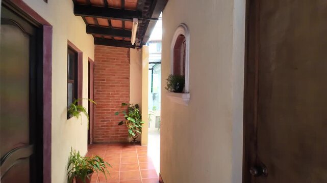 Sunlit hallway with wooden doors and arches in a colonial building