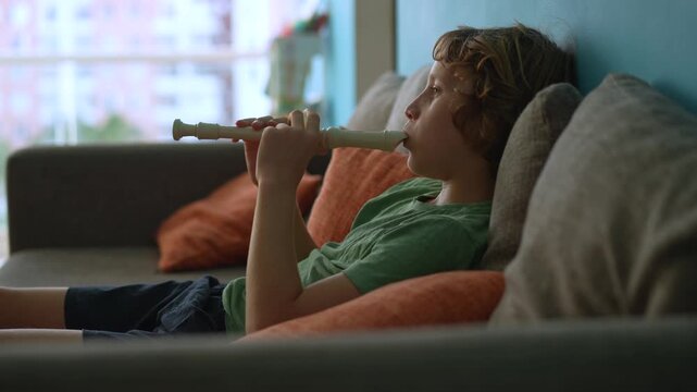 A little boy learns to play the flute at home, practicing with focus and enthusiasm in a cozy, warm setting. A charming scene of early musical exploration, creativity, and childhood growth.
