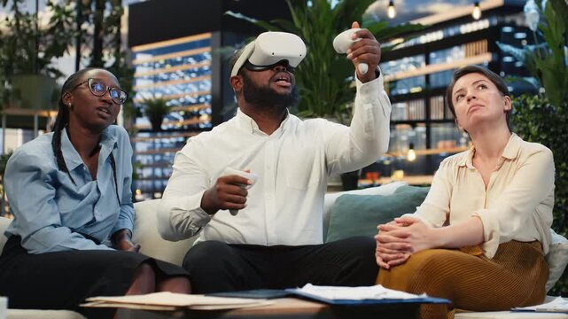 Close-up shows a businessman using a VR headset beside coworkers on a rooftop lounge; the professional explores immersive virtual reality technology with the team on the terrace workspace.
