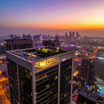 Modern skyscraper rooftop overlooking city skyline at sunset with glowing urban lights and high rise building