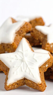 Star shaped spiced cookie with white icing and snowflake detail, surrounded by festive baked treats on light background