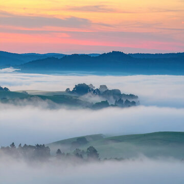 Misty mountain landscape with rolling green hills, forest, and pastel sunrise sky creating peaceful atmospheric panorama above cloud inversion