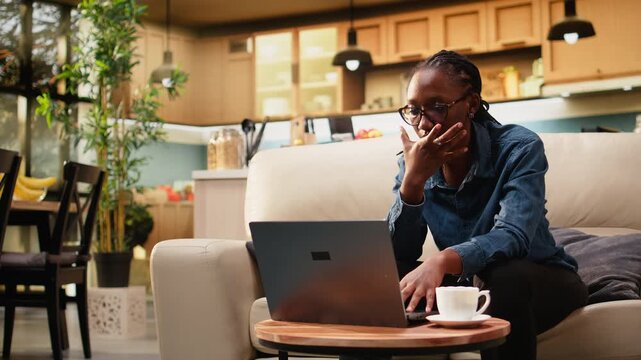 Overjoyed woman reacts to career good news and remote work reward after solving laptop tasks, showing emotion and ambition. She enjoys productivity and triumph while working from home in apartment.