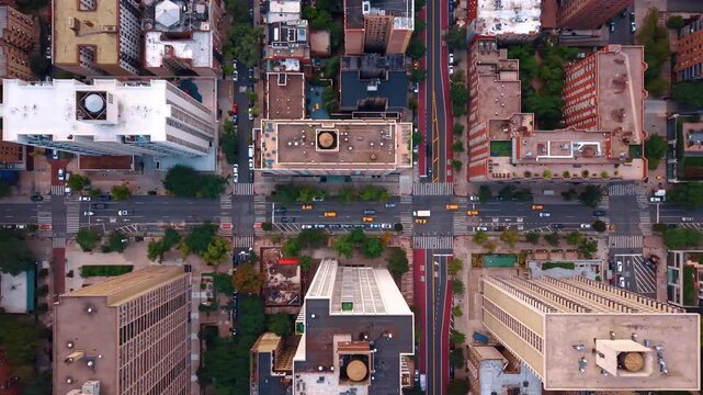Flow of cars with yellow taxis in moves by the long straight streets along the high-rise buildings. Top view on the neighborhood of modern New York City, USA from drone.