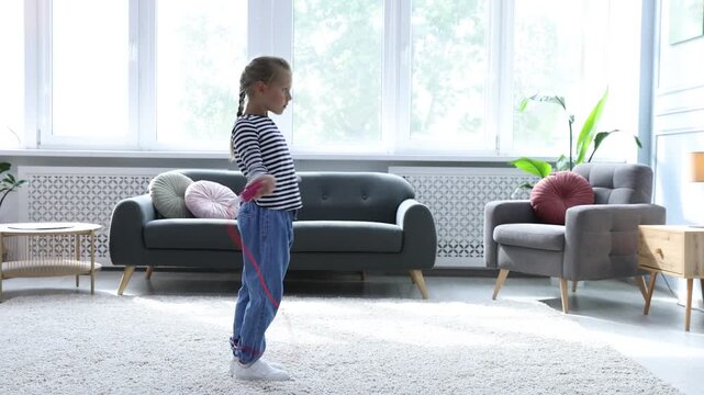 Cute little girl jumping with skipping rope at home