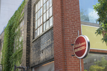 Obraz premium wall-mounted round projecting sign outside Oklahoma Burgers, a restaurant chain, located here at 45A Spadina Avenue, Toronto, just south of King Street West
