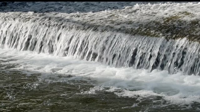 Bubbling water flows quickly over a weir, Mondsee, Salzkammergut, Austria