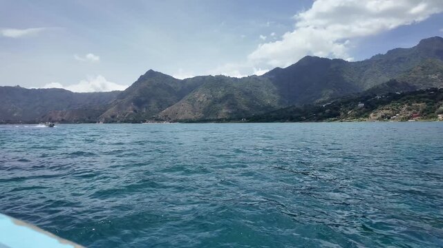 Lake Atitlan wide view with volcanic mountains and blue sky