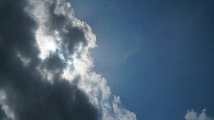 Fototapeta premium Sun Hidden Behind Dark Clouds in Blue Sky with Copy Space