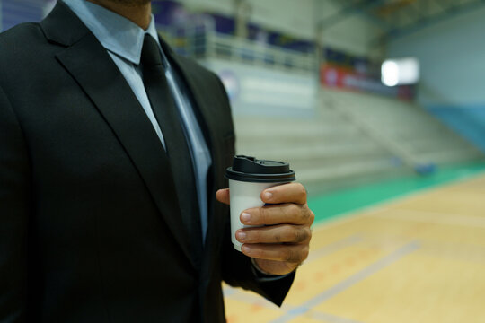 Focus on the executive's hands holding a coffee cup.