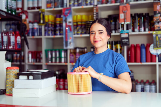Woman smiling, holding car air filter in an automotive supply shop