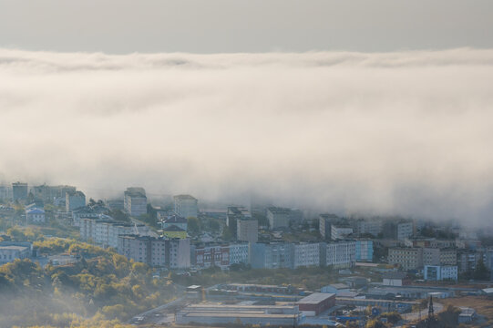 City in low clouds. Beautiful misty cityscape. Buildings in the clouds. View of the residential city blocks in the fog. Cloudy weather. Magadan, Magadan region, Siberia, Far East of Russia. Autumn.