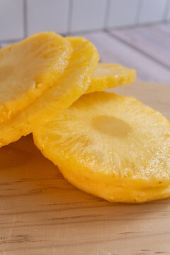 Freshly cut pineapple slices rest on wooden surface. Ideal for food, beverage. Perfect for menus, ads
