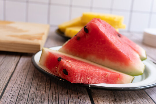 Fresh watermelon slices rest on a white plate