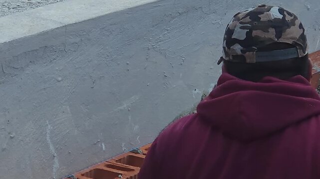 Mason applying cement on red clay bricks at construction site