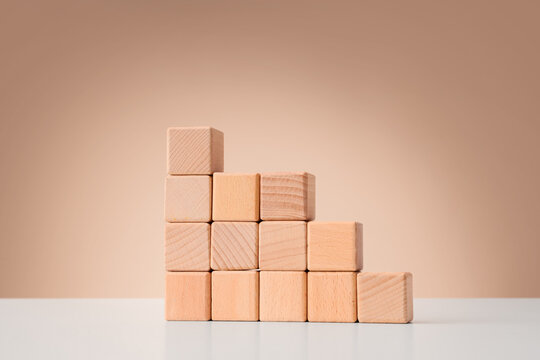 Business growth and development strategy, wooden blocks arranged in a descending staircase pattern on a table for corporate planning and progress