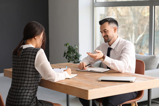 Human resources manager interviewing applicant at table in office