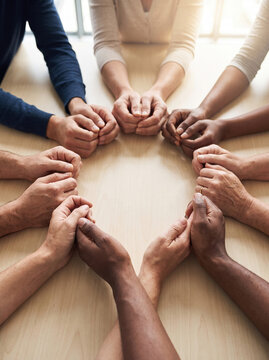 Hands forming protective circle around table with diverse people expressing unity and support