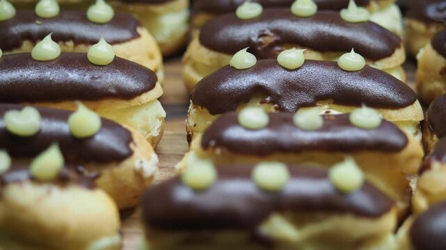 Chocolate eclairs being prepared and displayed in a bakery