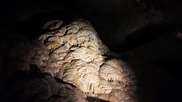Illuminated stalactite and stalagmite formations in a dark cave.