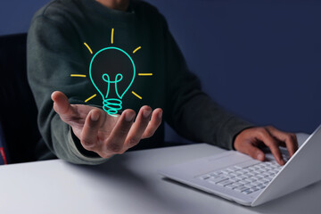 Person Displaying Hologram Illuminated Light Bulb Icon while Using Laptop © Queenmoonlite Studio