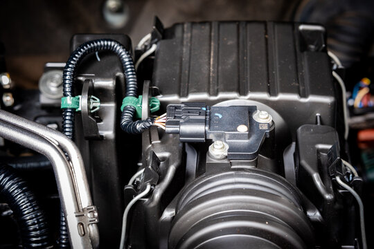 Close-up of an automotive throttle body and air intake assembly inside a modern vehicle engine compartment.