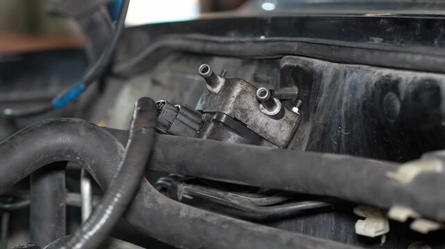 A close-up shot of an EGR solenoid valve mounted on the firewall inside a car engine bay, with disconnected vacuum ports and surrounding rubber hoses.