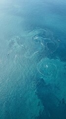 Obraz premium Breathtaking aerial view of turquoise ocean water with natural swirling patterns and ripples, showcasing pristine marine beauty.
