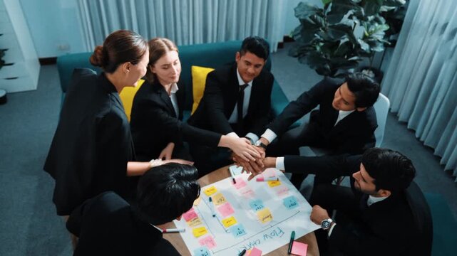 Top view of business people putting hands together and clapping hands to celebrate successful project while using kanban task board to manage time. Startup team stacking hands together. Directorate.