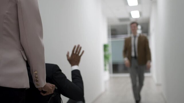 Coworkers say goodbye with a wave in office hallway