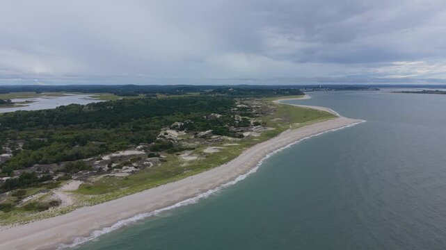 Forward drone fly toward Crane Beach shoreline borders dense coastal forest as gentle Atlantic waves meet the narrow barrier spit, Ipswich, Massachusetts, US