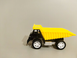 Yellow and black toy dump truck with raised cab, white wheels, and empty cargo bed isolated against a neutral background as a miniature construction vehicle © Ирина 