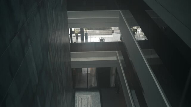 Transparent glass elevator cabin moving up inside a contemporary dark luxury hotel lobby