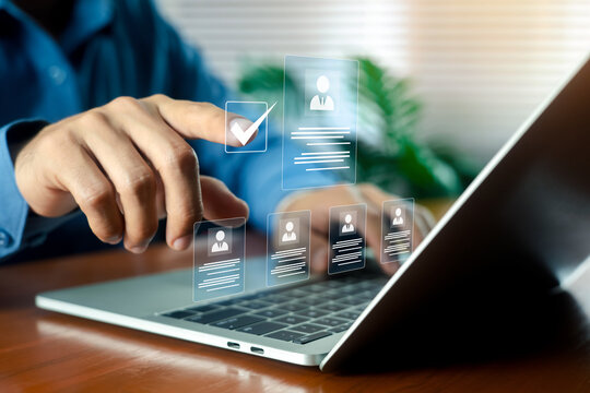 Businessman pointing at virtual resume and CV profiles interface on screen with laptop. Concept of human resources, hiring, recruitment, job interview, and talent acquisition management.