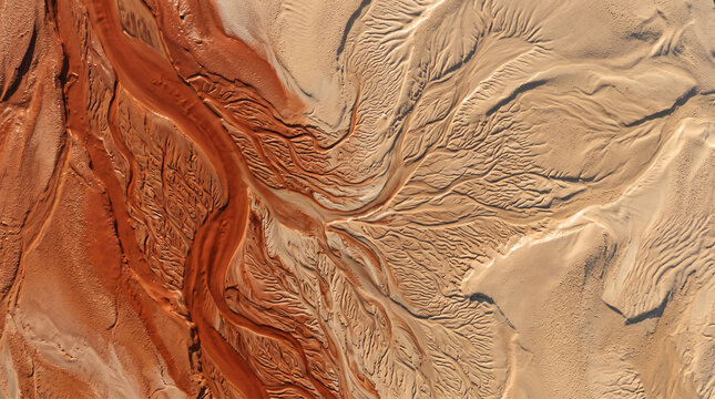 Abstract aerial landscape of red water flowing through sand forming branching dendritic textures