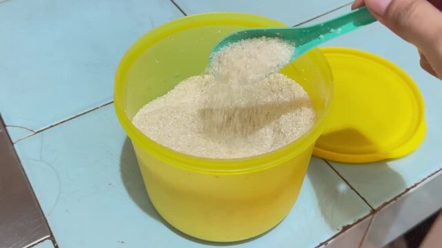 Video of granulated sugar inside a yellow container on a kitchen table.