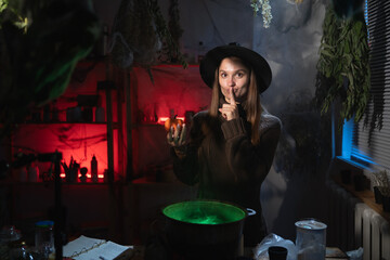 realistic witch brewing a potion in cauldron showing shh secret gesture cover his mouth. Blend of everyday life with traditional witchcraft, magic and mystical atmosphere © Andrii Lysenko