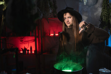 Realistic witch brewing a potion in cauldron showing thumb-down dislike gesture. Blend of everyday life with traditional witchcraft, magic and mystical atmosphere © Andrii Lysenko