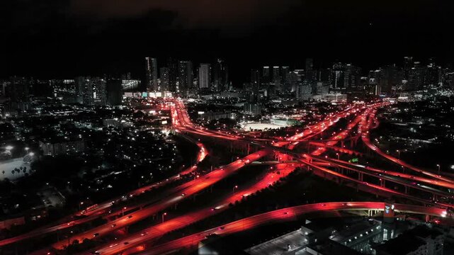 Cinematic night city hyperlapse panorama with glowing red traffic light trails. Dark dramatic aerial drone view of metropolitan skyscrapers center for cyberpunk or dystopian concept.
