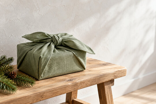 Geschenk in gr&uuml;nem Leinentuch mit Furoshiki-Knoten