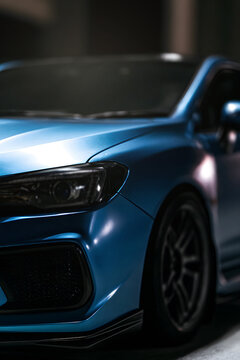 low angle close up view of a blue subaru wrx sti front at night with glowing led headlight parked outdoors to highlight rally performance car design, sports automobile tuning, and vehicle styling