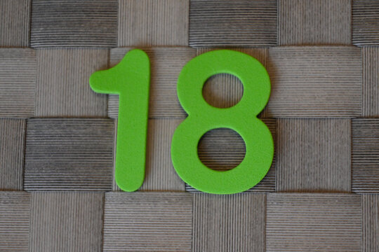 Green number 18 on a textured brown background